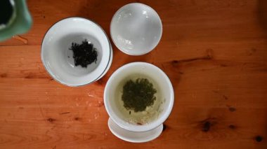 Bir fincan yeşil çaya sıcak su dökerek. Doğrudan yukarıdaki tahta masaya.