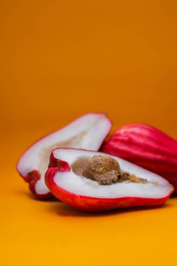 Jambu Bol veya Jambu Jamaika turuncu arka planda ayrıca Malay kırmızı gül elması olarak da bilinir (Syzygium Malaccense).