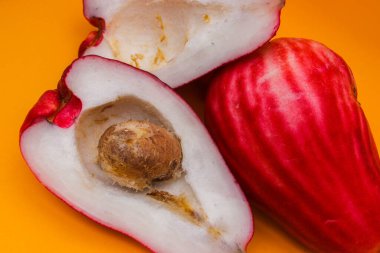 Jambu Bol veya Jambu Jamaika turuncu arka planda ayrıca Malay kırmızı gül elması olarak da bilinir (Syzygium Malaccense).