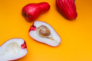 Jambu Bol veya Jambu Jamaika turuncu arka planda ayrıca Malay kırmızı gül elması olarak da bilinir (Syzygium Malaccense).