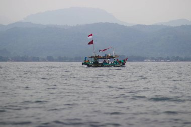 Sukabumi, Endonezya - 14 Haziran 2021: Endonezya 'nın Endonezya bölgesindeki Pelabuhan Ratu Sukabumi' de balık yakalamak için denize açılan Endonezya kırmızı-beyaz bayrağıyla bir grup balıkçı.