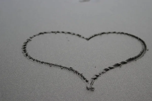 Arka Planda Yumuşak Dalgalar Olan Siyah Kumsalda Bir Kalp Sembolü — Stok fotoğraf