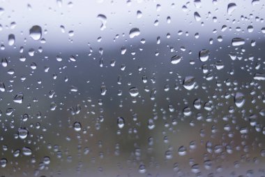 Yağmurdan sonra arabanın ön camındaki yağmur damlalarının odaklanmamış soyut arkaplanı