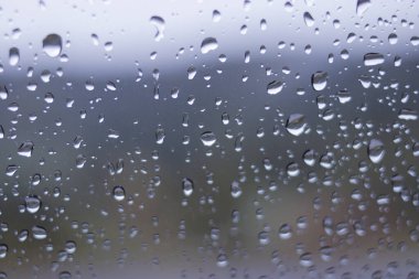 Yağmurdan sonra arabanın ön camındaki yağmur damlalarının odaklanmamış soyut arkaplanı