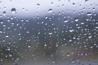 Yağmurdan sonra arabanın ön camındaki yağmur damlalarının odaklanmamış soyut arkaplanı