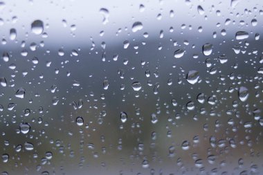 Yağmurdan sonra arabanın ön camındaki yağmur damlalarının odaklanmamış soyut arkaplanı