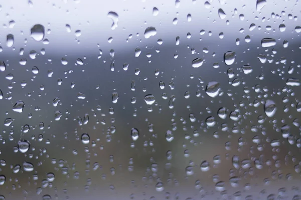 Yağmurdan sonra arabanın ön camındaki yağmur damlalarının odaklanmamış soyut arkaplanı