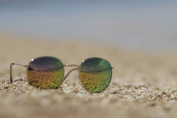 Defocused abstract background of sunglasses on sands in the beach with sky and seascape view reflection. Summer concept stock images