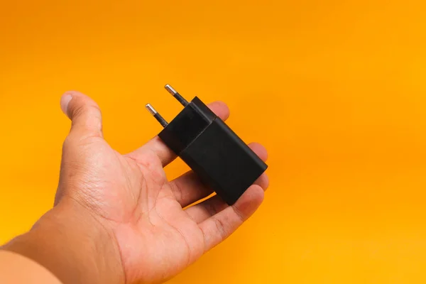 Black Cell Phone Charger Adapter Rękę Izolowane Pomarańczowym Tle — Zdjęcie stockowe