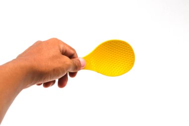 Beyaz arka planda sarı plastik pirinç kaşığı tutan Asyalı bir adam.