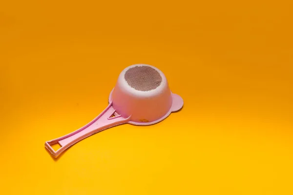 オレンジの背景に隔離された古い使用済みピンクのプラスチック製茶こし — ストック写真