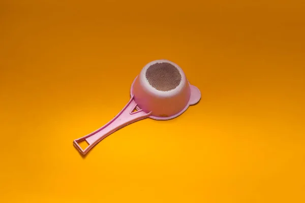 オレンジの背景に隔離された古い使用済みピンクのプラスチック製茶こし — ストック写真