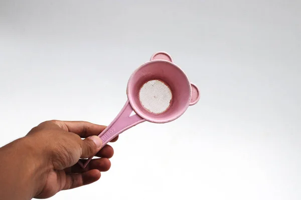 使用済みピンク色のプラスチック製茶こし を白地に手で隔離 — ストック写真