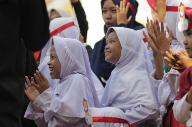 Purwakarta, Batı Java, Endonezya - 07 Eylül 2019: Beyaz ve kırmızı üniformalı Endonezyalı ilkokul öğrencileri arkadaşlarını alkışlıyorlar