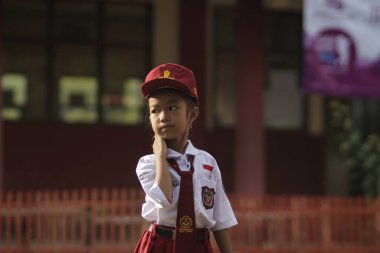 Sumedang, Batı Java, Endonezya - 21 Aralık 2019: Beyaz ve kırmızı üniformalı Endonezyalı bir ilkokul öğrencisi sınıfın önünde kırmızı şapkalı