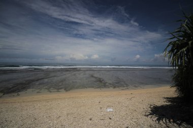 Mavi gökyüzü ve görkemli bulutlarıyla güzel tropik plaj Cibuaya Plajı Ujung Genteng Sukabumi, Batı Java, Endonezya.