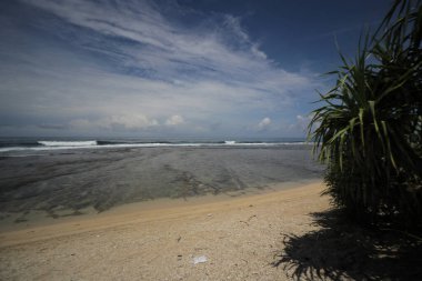 Mavi gökyüzü ve görkemli bulutlarıyla güzel tropik plaj Cibuaya Plajı Ujung Genteng Sukabumi, Batı Java, Endonezya.