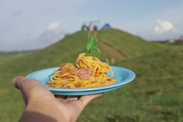 自家製スパゲティバジルの葉と青板の上にトウモロコシの牛肉を手に専用の緑の牧草地の背景と朝の青空 — ストック写真