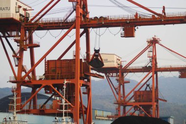 Sukabumi, Batı Java, Endonezya - 23 Ağustos 2021: Kömür ateşiyle çalışan buhar santralinin manzarası kanat vinci ile Pelabuhan Ratu kıyısı yakınlarındaki gemi kargosundan kömür stoklarını kaldırıyor..