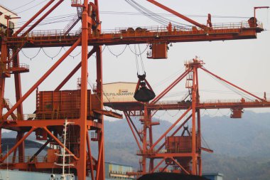 Sukabumi, Batı Java, Endonezya - 23 Ağustos 2021: Kömür ateşiyle çalışan buhar santralinin manzarası kanat vinci ile Pelabuhan Ratu kıyısı yakınlarındaki gemi kargosundan kömür stoklarını kaldırıyor..