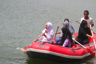 Sukabumi, Batı Java, Endonezya - 22 Ağustos 2021: Bir grup Endonezyalı, Batukarut Gölü veya Situ Batukarut Sukabumi, Batı Java, Endonezya 'da can yeleği giymeden şişme botta..