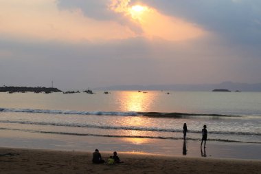 Sukabumi, Batı Java, Endonezya - 23 Ağustos 2021: Deniz manzaralı güzel gün batımı ve insanların silueti Batu Bintang Beach Pelabuhanratu Sukabumi West Java, Endonezya 'da günbatımının tadını çıkarıyor