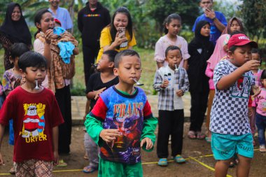 Sukabumi, Batı Java, Endonezya - 19 Ağustos 2021: Endonezya Bağımsızlık Günü boyunca Endonezya 'nın geleneksel oyunu Balap Kereveng veya Mermer Yarışı adı verilen bir grup mutlu Endonezyalı çocuk oynuyor.