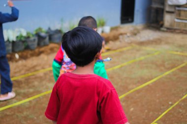 Sukabumi, Batı Java, Endonezya - 19 Ağustos 2021: Endonezya Bağımsızlık Günü boyunca Endonezya 'nın geleneksel oyunu Balap Kereveng veya Mermer Yarışı adı verilen bir grup mutlu Endonezyalı çocuk oynuyor.