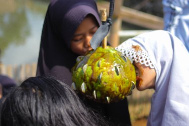 Sukabumi, Batı Java, Endonezya - 19 Ağustos 2021: Endonezyalı çocuklar SIGIT adı verilen geleneksel oyunlar oynuyorlar veya Endonezya Bağımsızlık Günü sırasında soya sosuyla kaplı portakal meyvelerinden madeni para alıyorlar