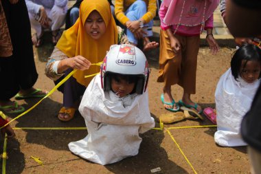 Sukabumi, Batı Java, Endonezya - 19 Ağustos 2021: Endonezyalı miğferli bir grup çocuk Endonezya 'nın Bağımsızlık Günü' nde Balap Karung veya Sack Race adlı geleneksel oyunlarıyla mücadele ediyor