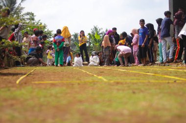 Sukabumi, Batı Java, Endonezya - 19 Ağustos 2021: Endonezyalı miğferli bir grup çocuk Endonezya 'nın Bağımsızlık Günü' nde Balap Karung veya Sack Race adlı geleneksel oyunlarıyla mücadele ediyor