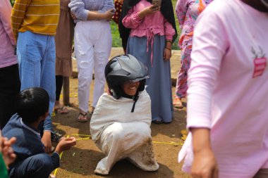 Sukabumi, Batı Java, Endonezya - 19 Ağustos 2021: Endonezyalı miğferli bir grup çocuk Endonezya 'nın Bağımsızlık Günü' nde Balap Karung veya Sack Race adlı geleneksel oyunlarıyla mücadele ediyor