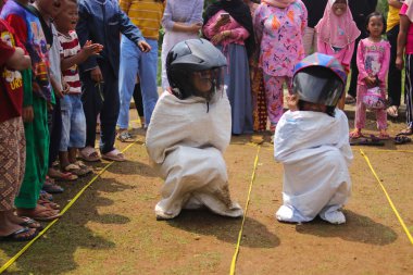 Sukabumi, Batı Java, Endonezya - 19 Ağustos 2021: Endonezyalı miğferli bir grup çocuk Endonezya 'nın Bağımsızlık Günü' nde Balap Karung veya Sack Race adlı geleneksel oyunlarıyla mücadele ediyor