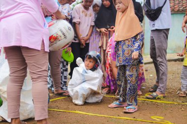 Sukabumi, Batı Java, Endonezya - 19 Ağustos 2021: Endonezyalı miğferli bir grup çocuk Endonezya 'nın Bağımsızlık Günü' nde Balap Karung veya Sack Race adlı geleneksel oyunlarıyla mücadele ediyor