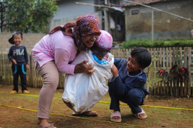 Sukabumi, Batı Java, Endonezya - 19 Ağustos 2021: Endonezyalı miğferli bir grup çocuk Endonezya 'nın Bağımsızlık Günü' nde Balap Karung veya Sack Race adlı geleneksel oyunlarıyla mücadele ediyor