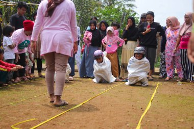 Sukabumi, Batı Java, Endonezya - 19 Ağustos 2021: Endonezyalı miğferli bir grup çocuk Endonezya 'nın Bağımsızlık Günü' nde Balap Karung veya Sack Race adlı geleneksel oyunlarıyla mücadele ediyor