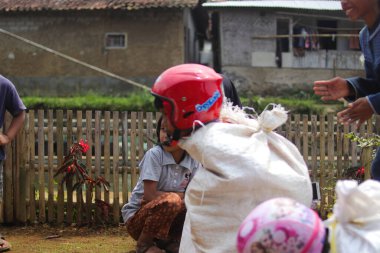 Sukabumi, Batı Java, Endonezya - 19 Ağustos 2021: Endonezyalı miğferli bir grup çocuk Endonezya 'nın Bağımsızlık Günü' nde Balap Karung veya Sack Race adlı geleneksel oyunlarıyla mücadele ediyor