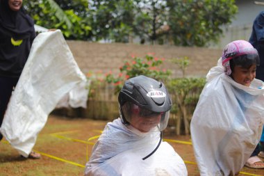 Sukabumi, Batı Java, Endonezya - 19 Ağustos 2021: Endonezyalı miğferli bir grup çocuk Endonezya 'nın Bağımsızlık Günü' nde Balap Karung veya Sack Race adlı geleneksel oyunlarıyla mücadele ediyor