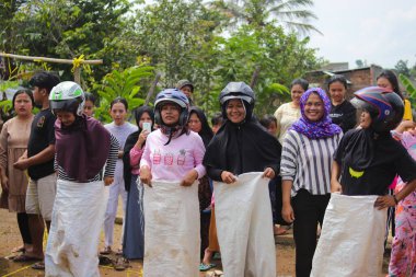 Sukabumi, Batı Java, Endonezya - 19 Ağustos 2021: Endonezyalı miğferli bir grup kadın Endonezya Bağımsızlık Günü 'nde Balap Karung veya Sack Race adlı geleneksel Endonezya oyunlarıdır.