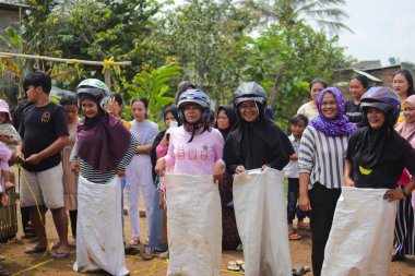 Sukabumi, Batı Java, Endonezya - 19 Ağustos 2021: Endonezyalı miğferli bir grup kadın Endonezya Bağımsızlık Günü 'nde Balap Karung veya Sack Race adlı geleneksel Endonezya oyunlarıdır.