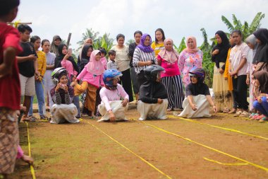 Sukabumi, Batı Java, Endonezya - 19 Ağustos 2021: Endonezyalı miğferli bir grup kadın Endonezya Bağımsızlık Günü 'nde Balap Karung veya Sack Race adlı geleneksel Endonezya oyunlarıdır.