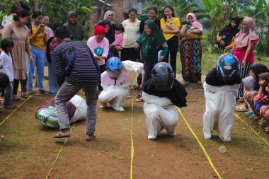 Sukabumi, Batı Java, Endonezya - 19 Ağustos 2021: Endonezyalı miğferli bir grup kadın Endonezya Bağımsızlık Günü 'nde Balap Karung veya Sack Race adlı geleneksel Endonezya oyunlarıdır.