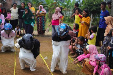 Sukabumi, Batı Java, Endonezya - 19 Ağustos 2021: Endonezyalı miğferli bir grup kadın Endonezya Bağımsızlık Günü 'nde Balap Karung veya Sack Race adlı geleneksel Endonezya oyunlarıdır.