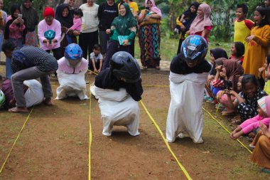 Sukabumi, Batı Java, Endonezya - 19 Ağustos 2021: Endonezyalı miğferli bir grup kadın Endonezya Bağımsızlık Günü 'nde Balap Karung veya Sack Race adlı geleneksel Endonezya oyunlarıdır.