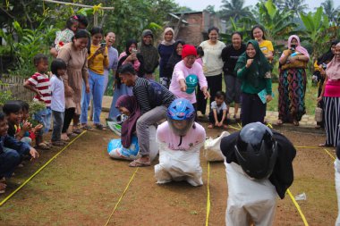 Sukabumi, Batı Java, Endonezya - 19 Ağustos 2021: Endonezyalı miğferli bir grup kadın Endonezya Bağımsızlık Günü 'nde Balap Karung veya Sack Race adlı geleneksel Endonezya oyunlarıdır.