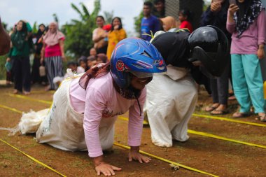 Sukabumi, Batı Java, Endonezya - 19 Ağustos 2021: Endonezyalı miğferli bir grup kadın Endonezya Bağımsızlık Günü 'nde Balap Karung veya Sack Race adlı geleneksel Endonezya oyunlarıdır.