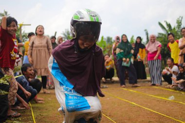 Sukabumi, Batı Java, Endonezya - 19 Ağustos 2021: Endonezyalı miğferli bir grup kadın Endonezya Bağımsızlık Günü 'nde Balap Karung veya Sack Race adlı geleneksel Endonezya oyunlarıdır.