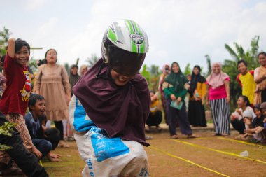 Sukabumi, Batı Java, Endonezya - 19 Ağustos 2021: Endonezyalı miğferli bir grup kadın Endonezya Bağımsızlık Günü 'nde Balap Karung veya Sack Race adlı geleneksel Endonezya oyunlarıdır.