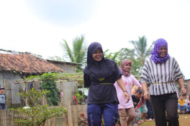 Sukabumi, Batı Java, Endonezya - 19 Ağustos 2021: Bir grup mutlu Endonezyalı kadın, Endonezya Bağımsızlık Günü boyunca şişeye kalem koymak için yarışırken gülüyor