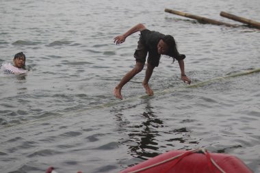 Sukabumi, Batı Java, Endonezya - 22 Ağustos 2021: Endonezyalı bir adam bambu üzerinde yürümeye çalışırken suya düşer ve Endonezya Bağımsızlık Günü boyunca Panjat Pinang adı verilen geleneksel oyunları oynamaya çalışır